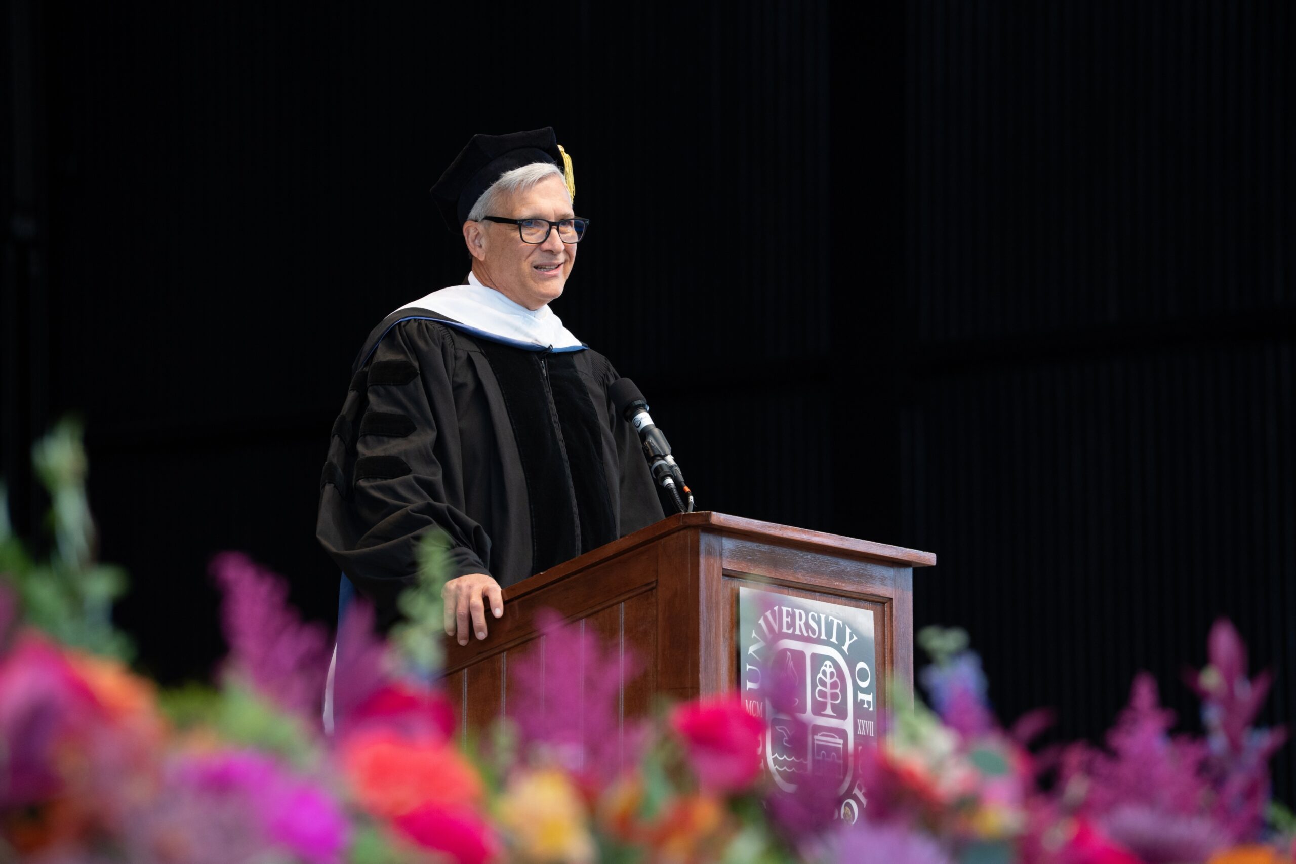Man in graduation gown standing at a podium