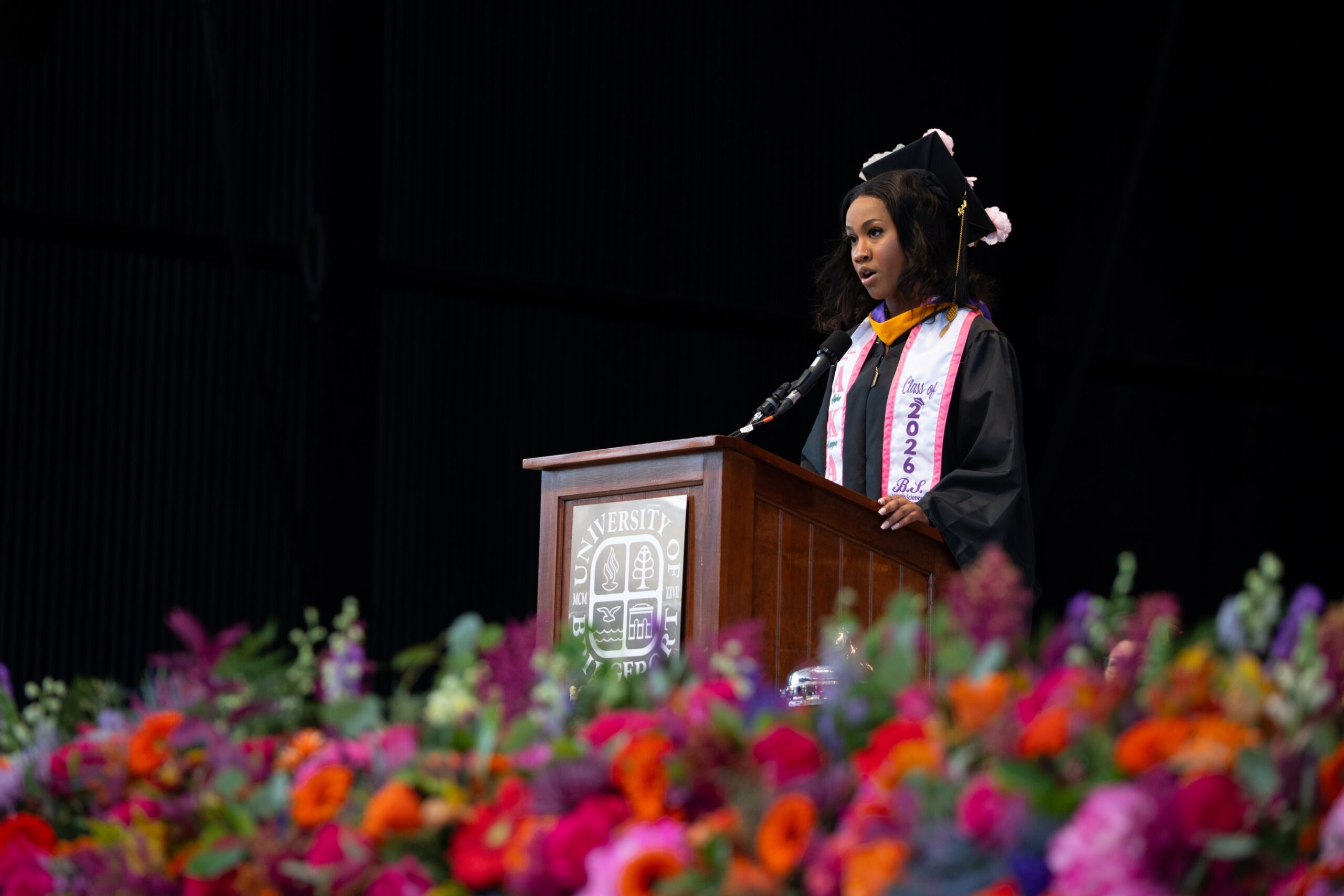 Women in graduation gown standing at a podium.
