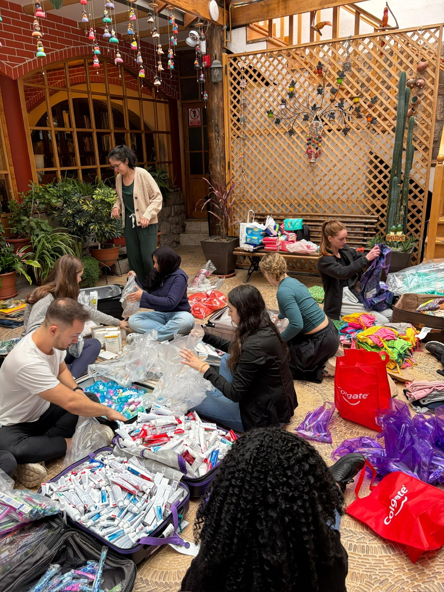 6 PA students sitting on the ground surrounded by suitcases filled with medical supplies for care kits.
