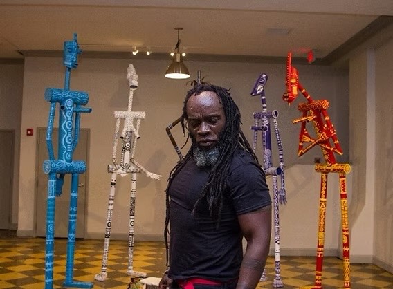 Iyaba Ibo Mandingo posing in front of three sculptures