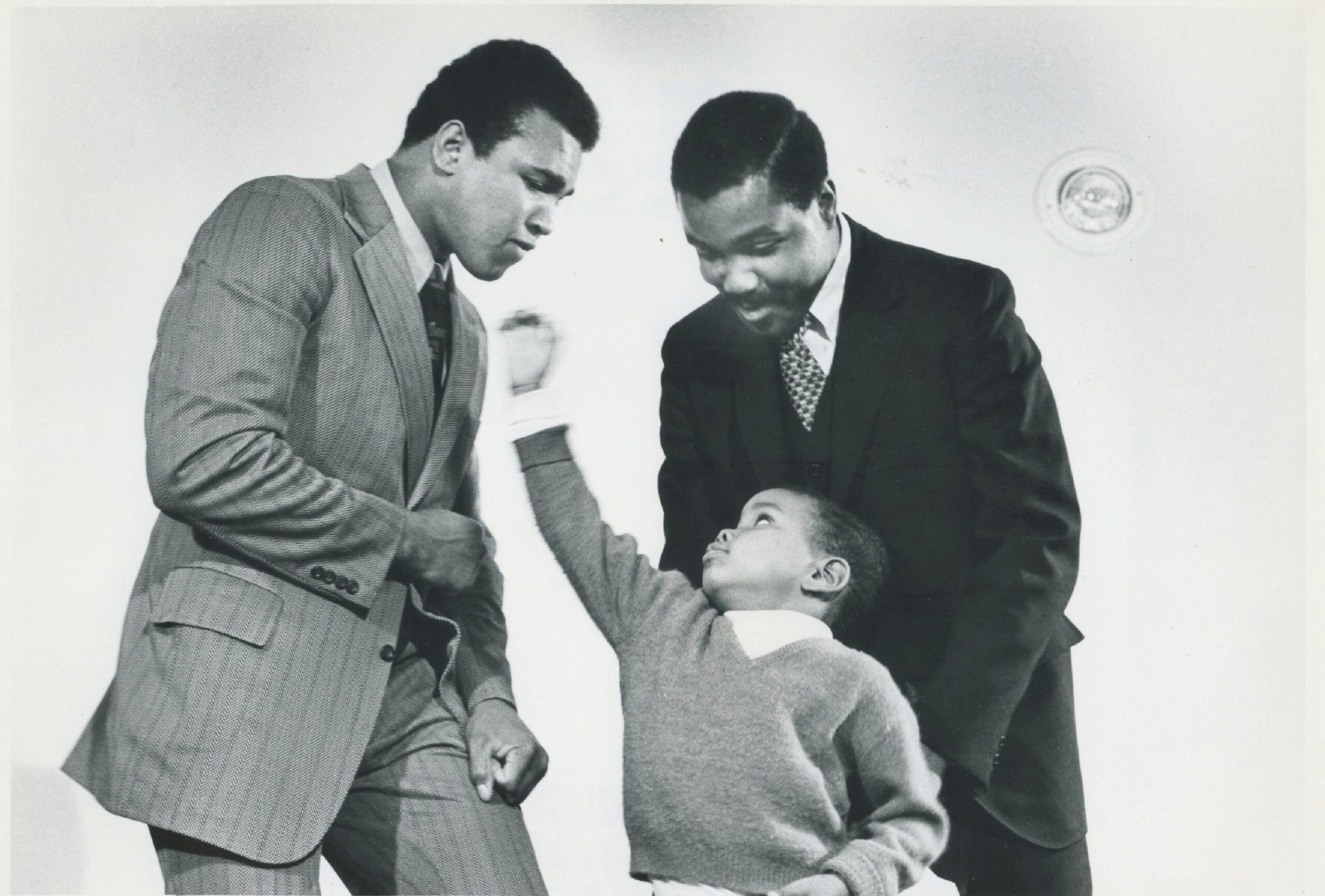 Photograph of Muhammad Ali joking with a young fan at University of Bridgeport in 1971.