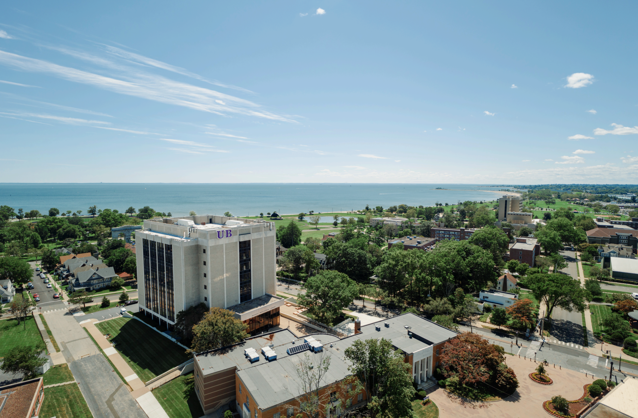 Aerial drone view of the University of Bridgeport campus in Bridgeport, Connecticut, showcasing Wahlstrom Library and the scenic shoreline of Long Island Sound.