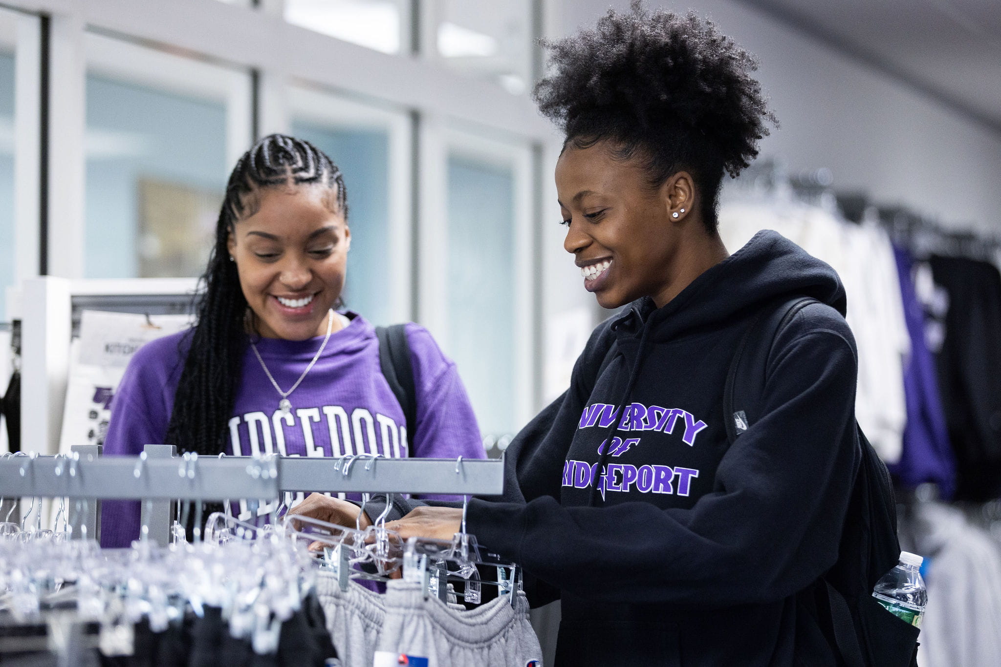 Two students browse a rack of clothing in the bookstore.