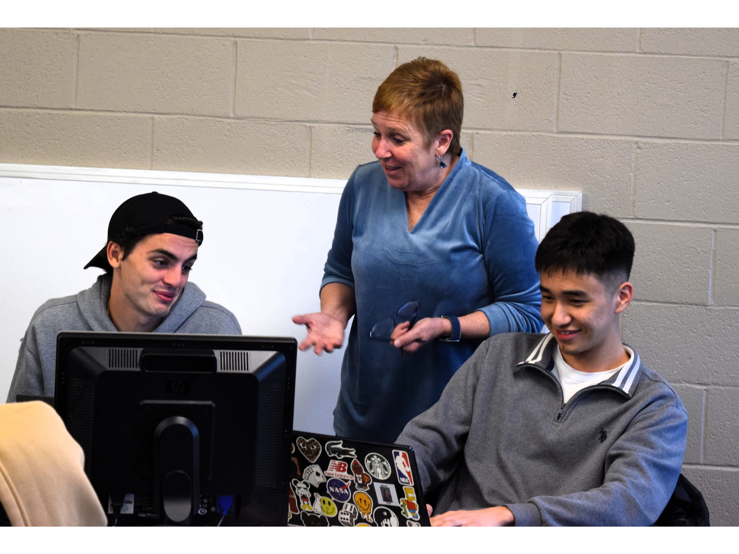 College professor instructing students in a computer lab setting.